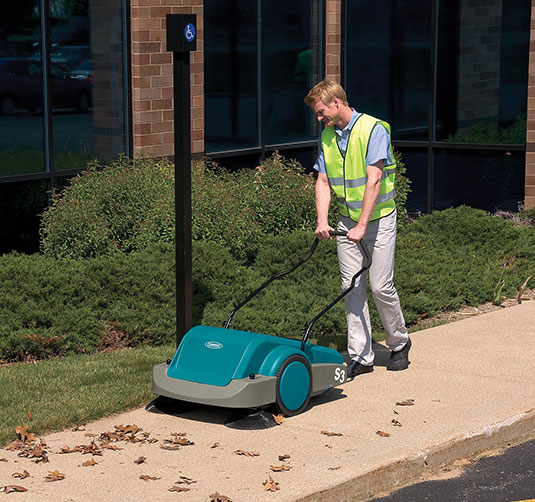 S3 Manual Sweeper sweeping a sidewalk.